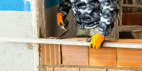 Bricklayer installing brick masonry on interior wall. Bricklayer installing brick masonry on interior wall.